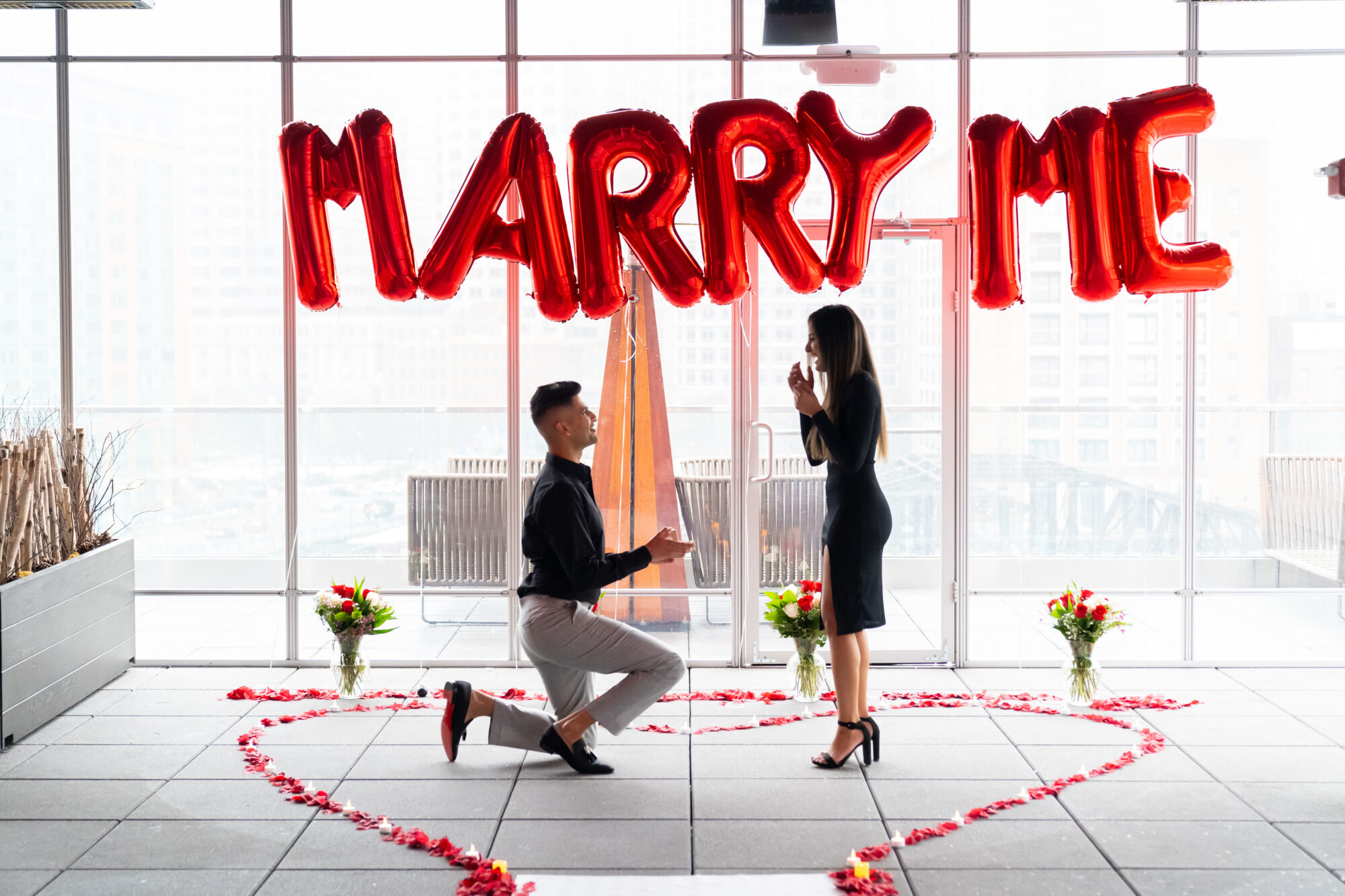 A Boston proposal photographer captures an intimate moment as a man and woman kneel in front of a "marry me" balloon.