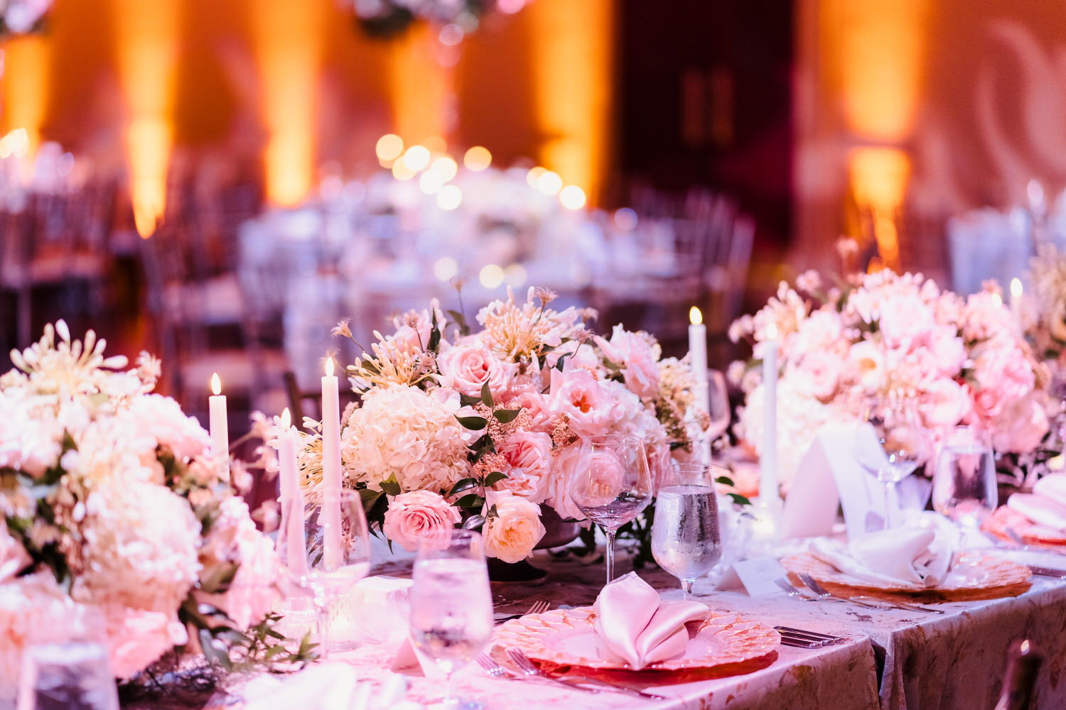 A wedding table set with pink flowers and candles.