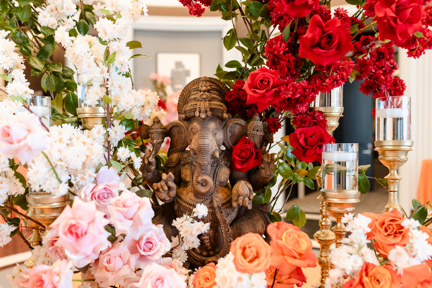 A table filled with flowers and a statue of ganesha.