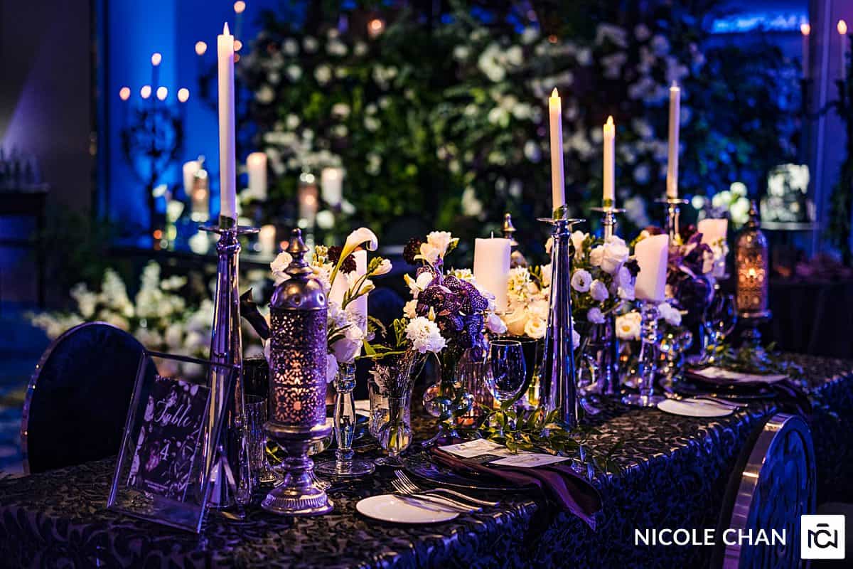 A black and white table setting with candles and flowers.