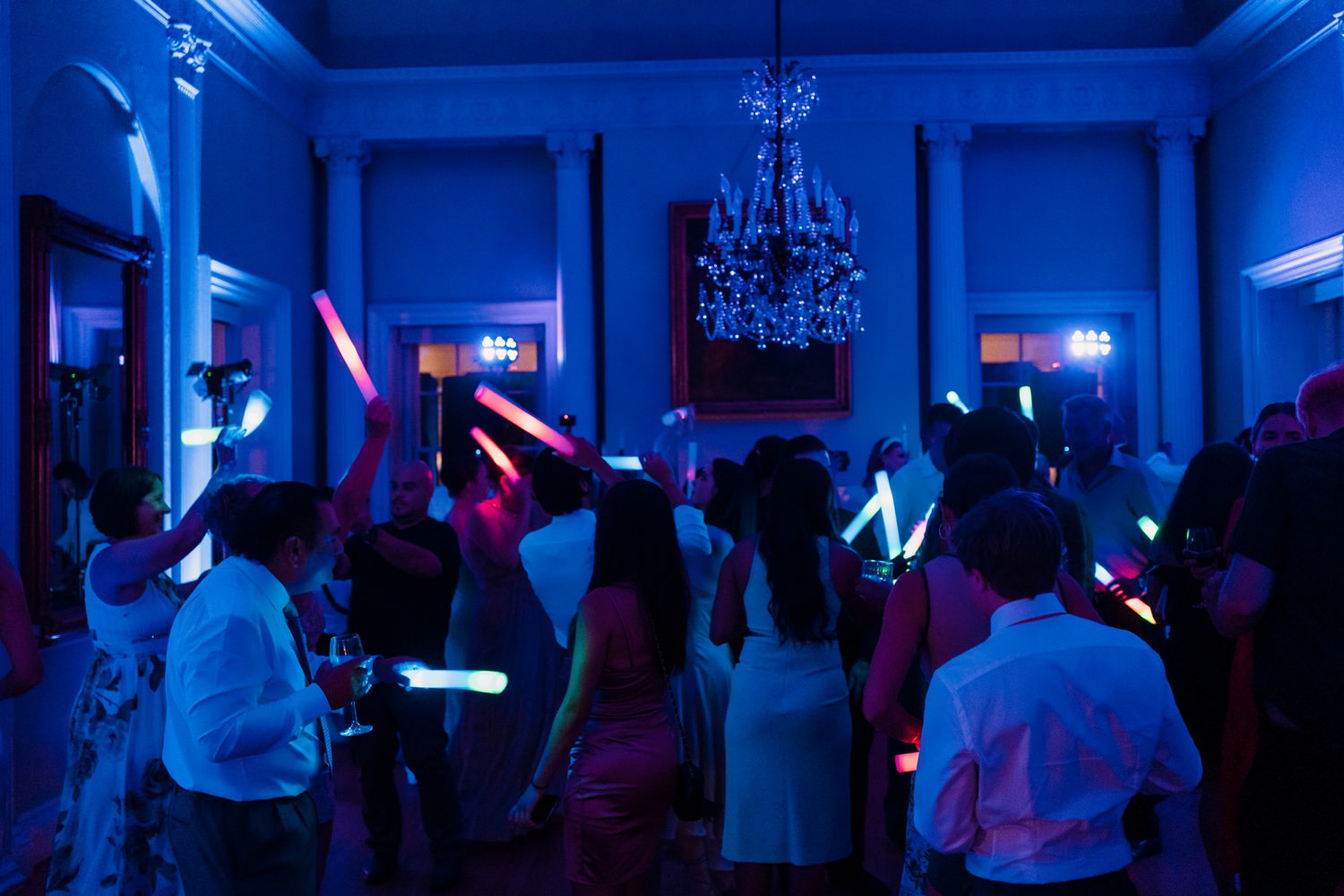 A group of people holding up light sabers in a dark room.