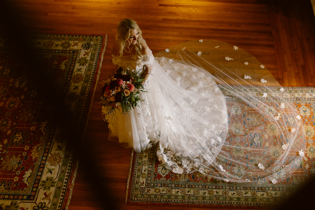 A bride in a wedding dress standing on a rug.