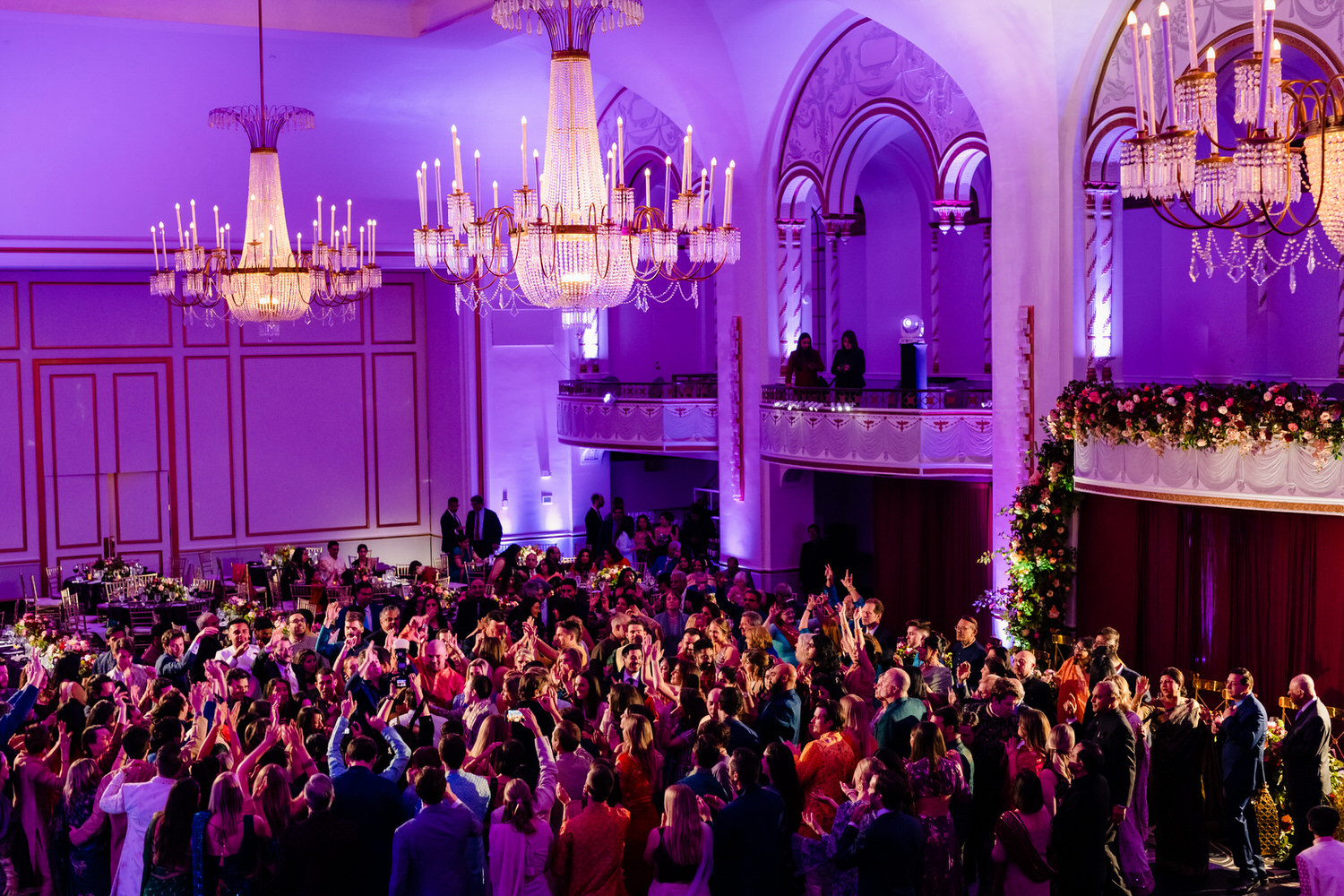 A large group of people in a room with chandeliers.