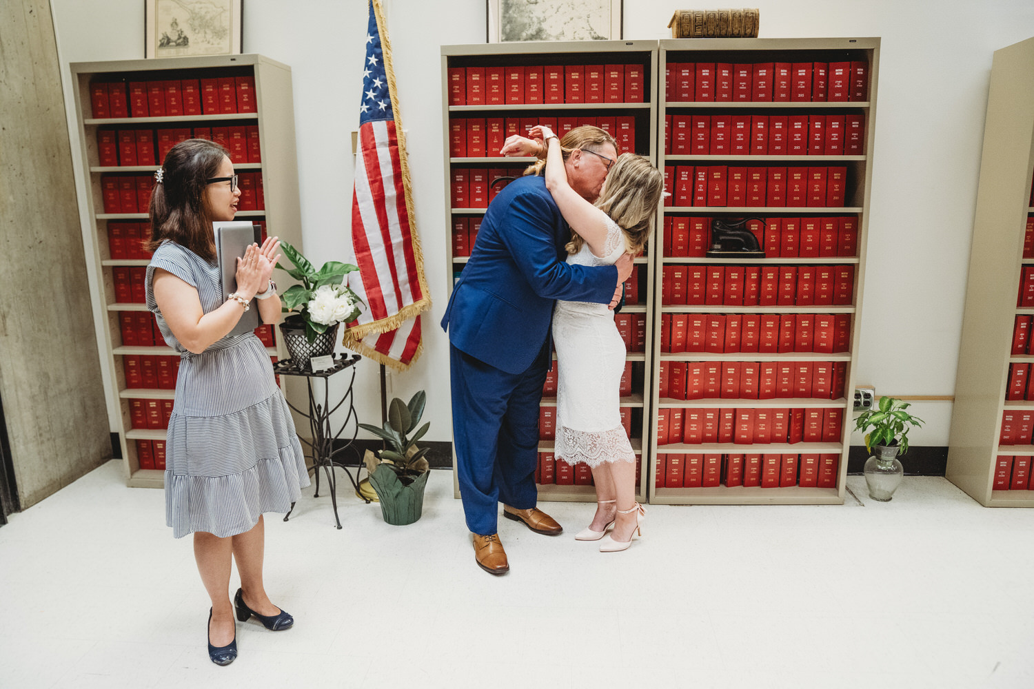 A couple exchanging vows in front of a bookcase at their Boston City Hall wedding.