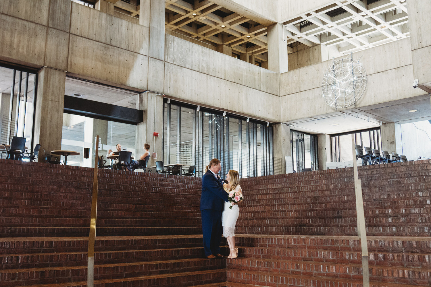A bride and groom in front of Boston City Hall.
