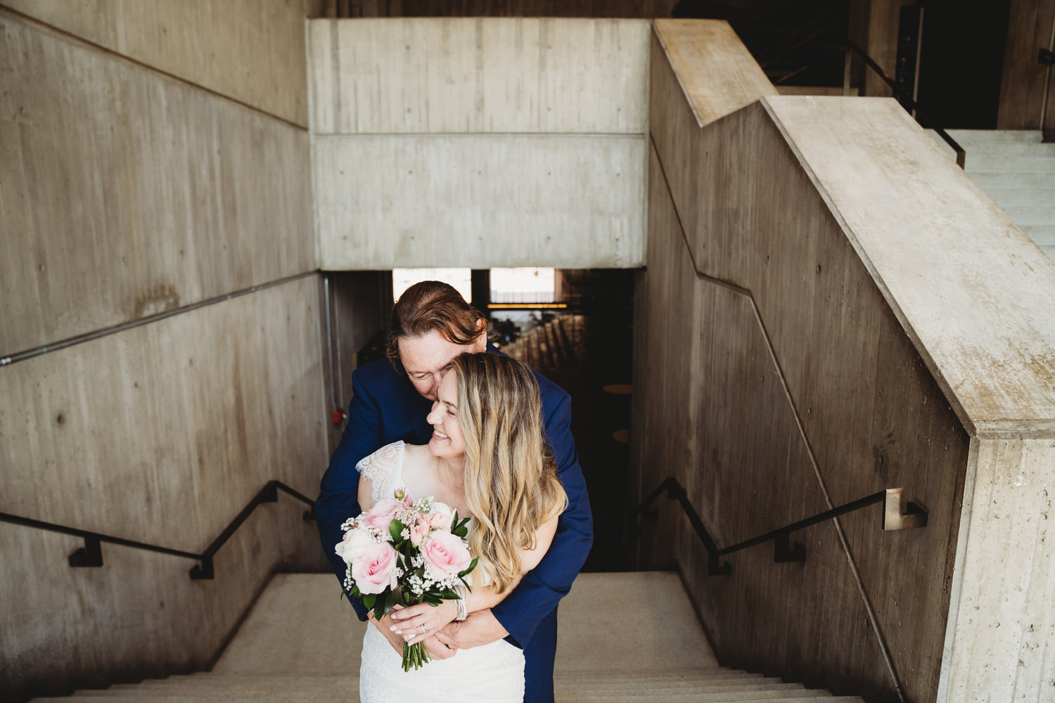 A bride and groom hugging on the steps of Boston City Hall after their wedding.